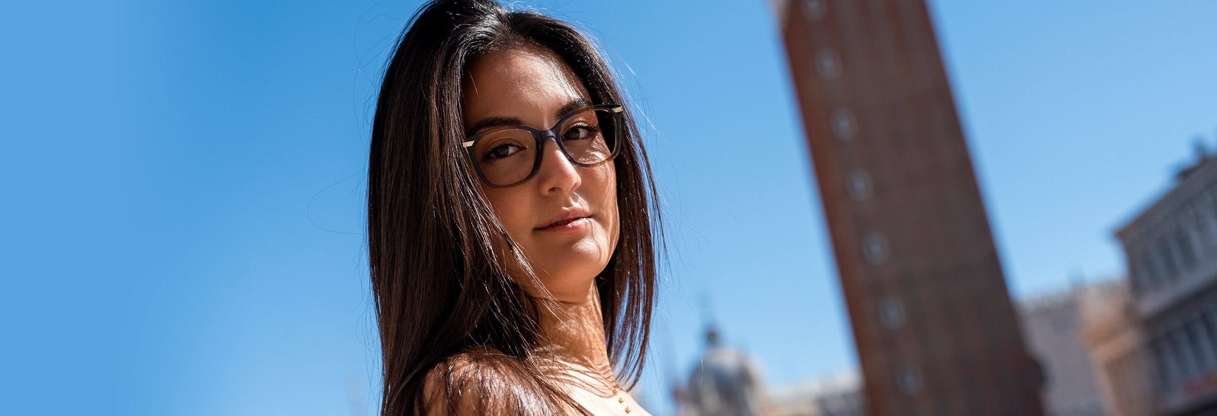 A woman wearing Bauta glasses, framed by a blue sky