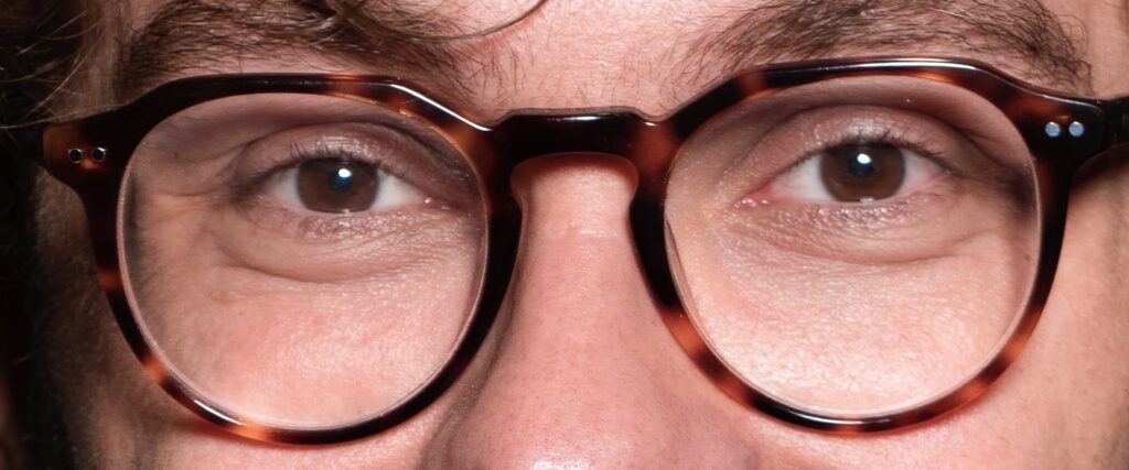Close-up of brown-eyed man wearing round tortoiseshell frames