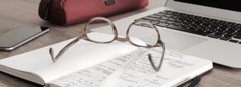 Pair of glasses upside down on top of an opened notepad