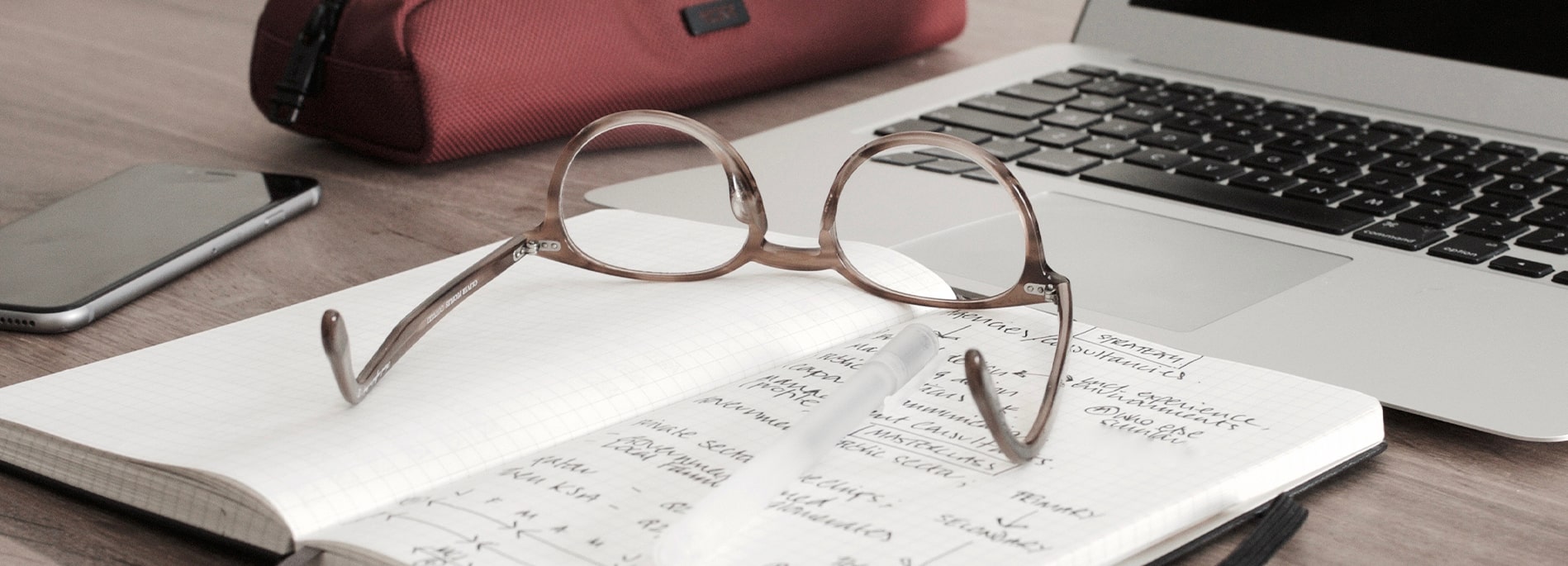 Pair of glasses upside down on top of an opened notepad