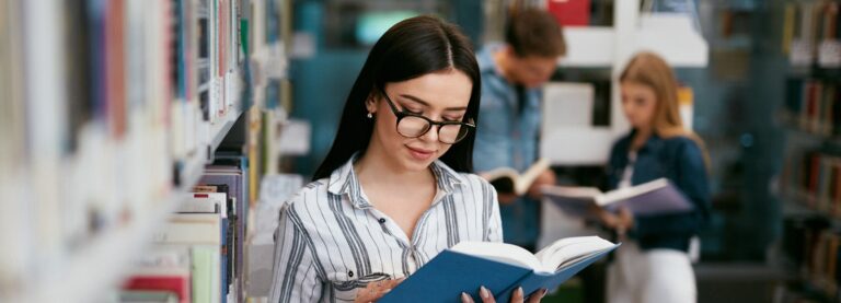 Female universtiy student reading a book in the library