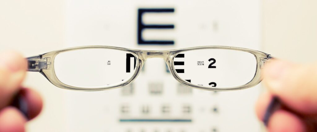 Pair of rectangular slim frames held up to eye test letter board