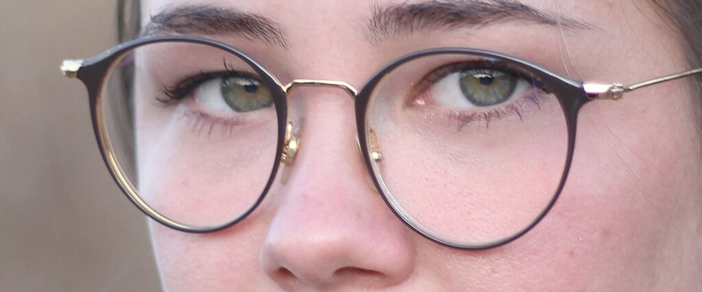 Close-up of frame with green eyes wearing glasses, looking straight at you