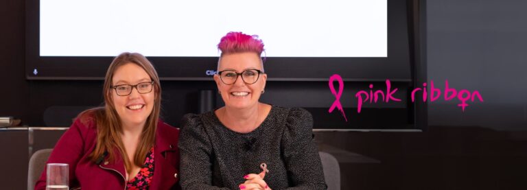 Close-up image of two ladies wearing Pink Ribbon frames looking straight at the camera