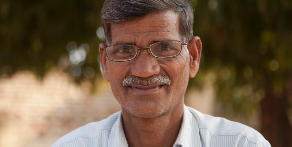 Older male wearing glasses smiling at the camera