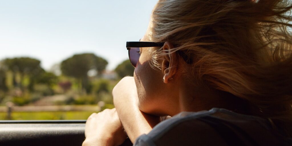 Woman wearing sunglasses looking out of a car window