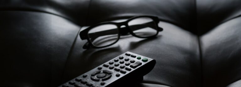 Glasses and TV remote on a sofa