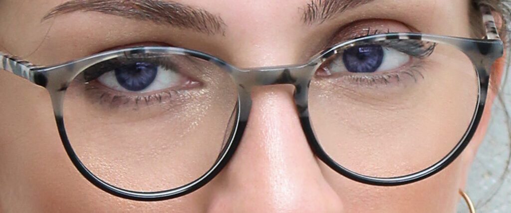 Female wearing glasses with violet coloured eye colour