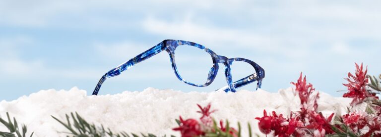 The Collection Andi glasses in the Tanzanite colour lying in a snowy landscape