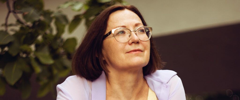 Older woman wearing cat-eye frames looking into the distance