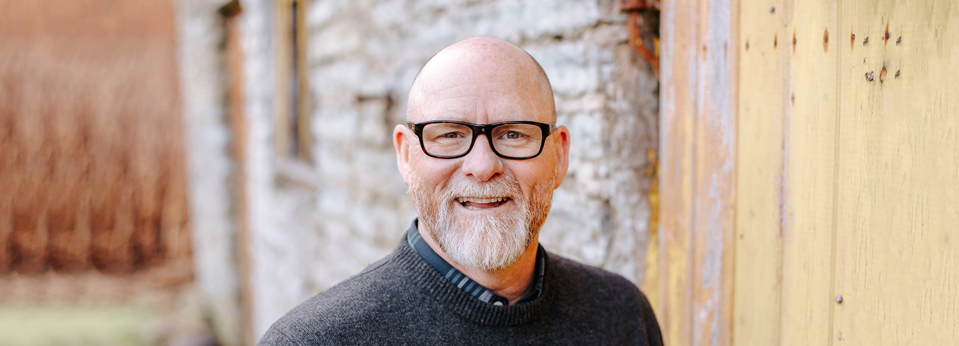 Older man wearing rectangular black frames smiling