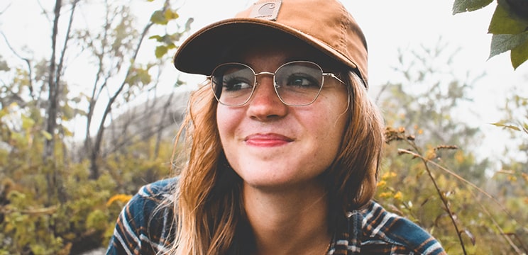 Woman wearing round glasses posing for a selfie while looking into the distance