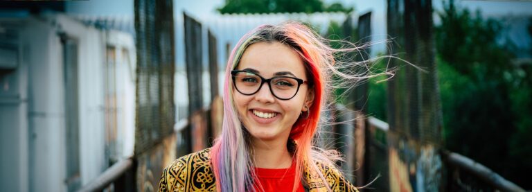 Woman outdoors wearing cat-eye glasses smiling