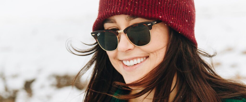 Woman wearing wooly hat and sunglasses smiling