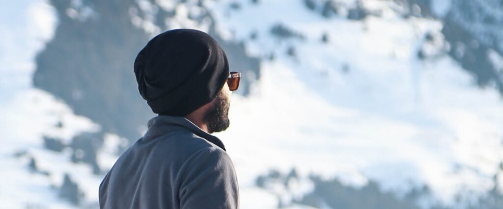 Man wearing sunglasses looking into a snowy distance 