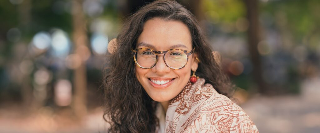 Woman wearing large round tortoiseshell frames smiling