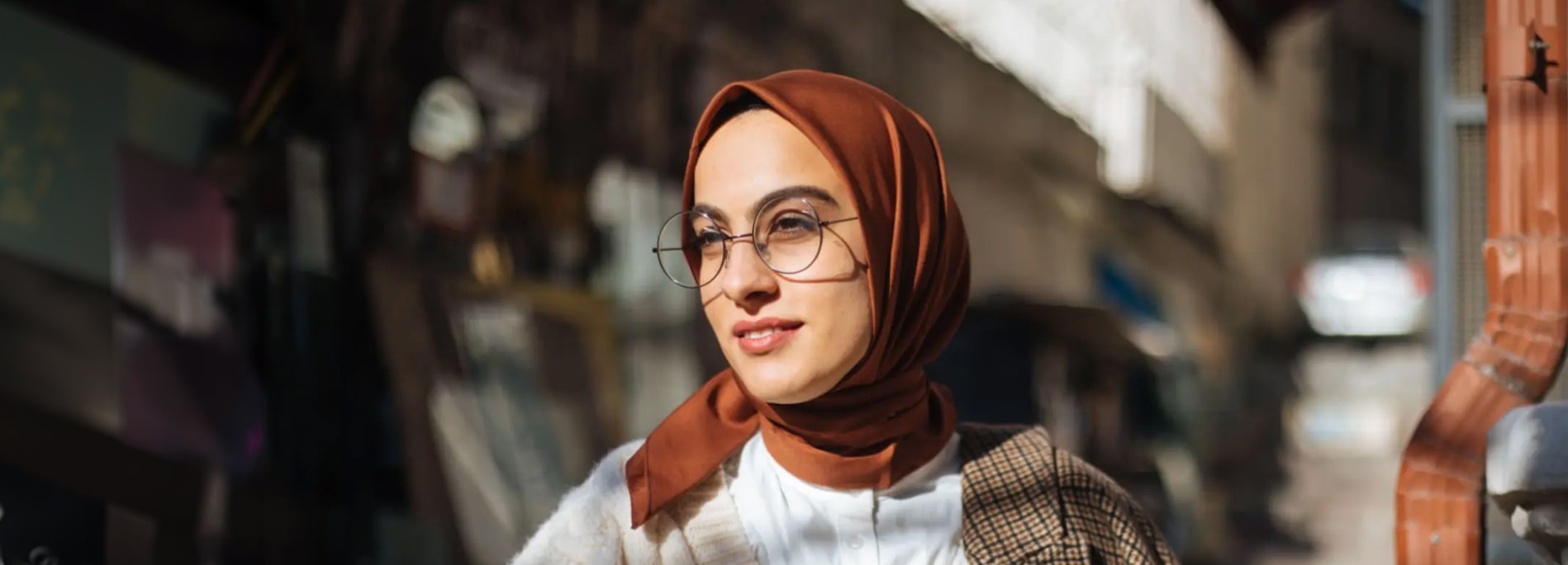 Woman wearing a brown hijab and metal glasses outdoors