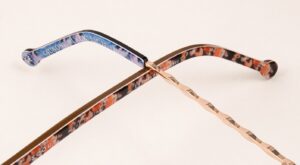 Close-up of two frame arms, one with orange floral patterns and one with gold metal and blue floral patterns crossing one another
