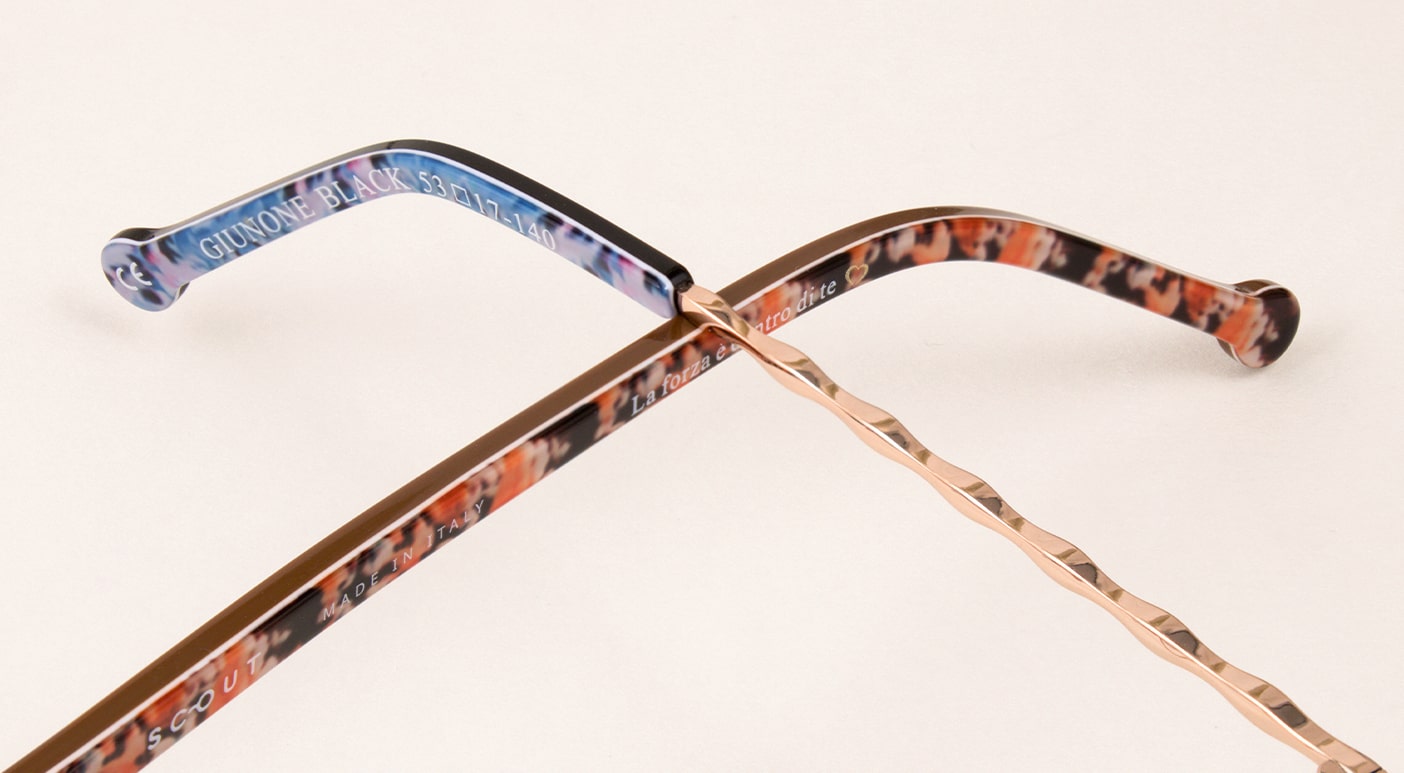 Close-up of two frame arms, one with orange floral patterns and one with gold metal and blue floral patterns crossing one another
