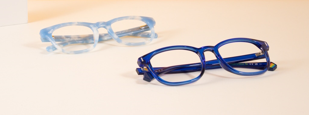 A light and a dark blue glasses frame lying on a cream surface
