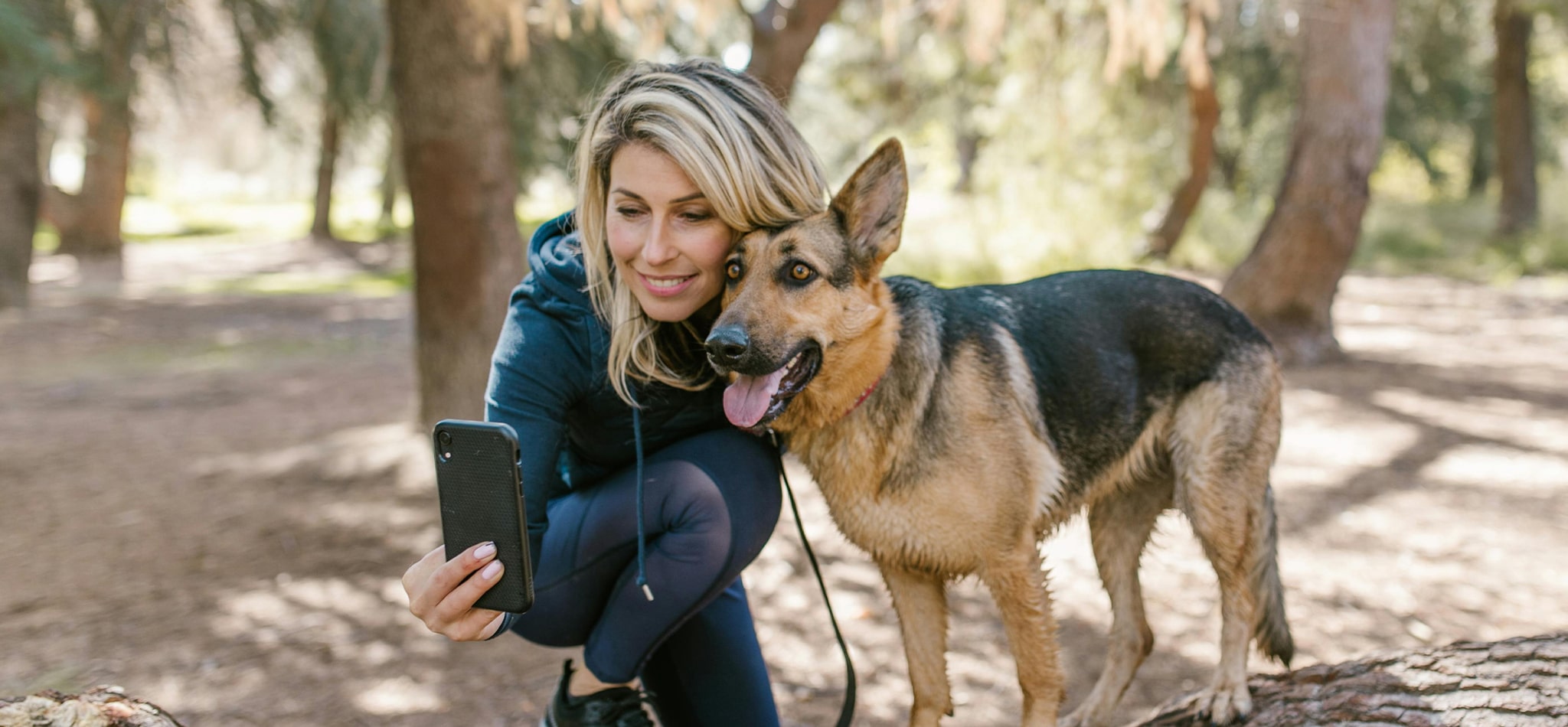 Woman taking a selfie with her dog outdoors in a forest