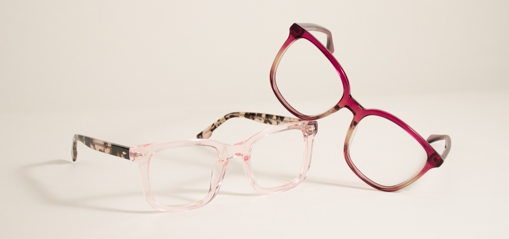 A light pink frame with tortoiseshell arms with a dark gradient pink frame leaning against it
