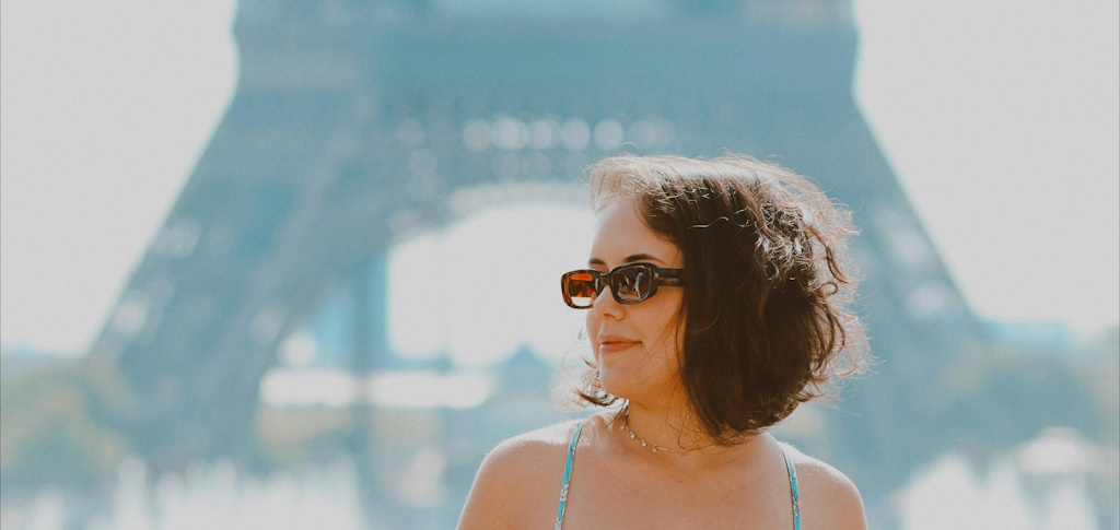 A smiling woman wearing sunglasses in front of the Eiffel tower