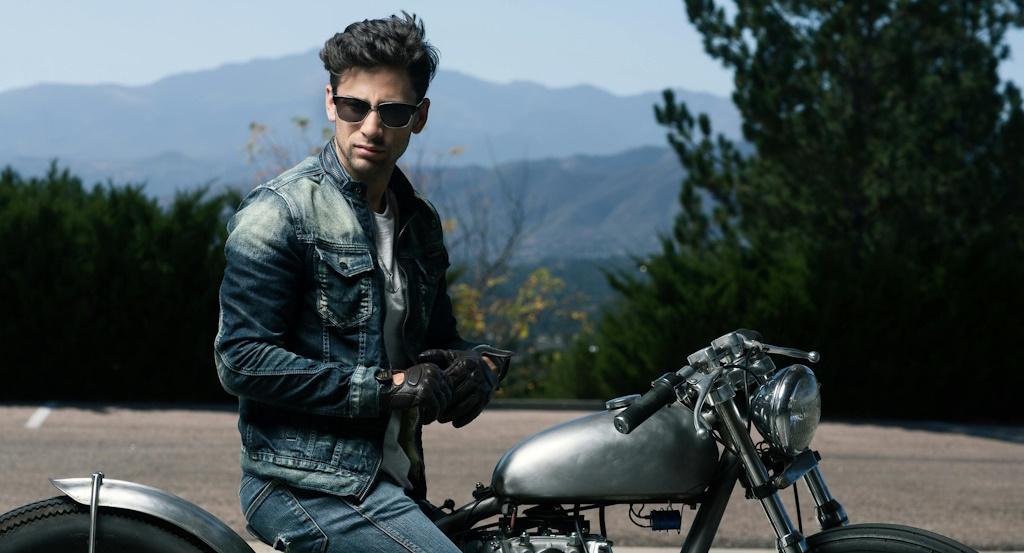 A man in sunglasses pausing on the side of the road during a motorbike ride across the countryside